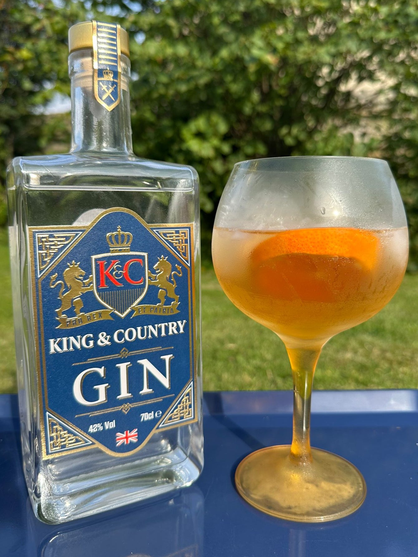 King & Country Gin bottle with a glass of K&C Sunset cocktail outdoors