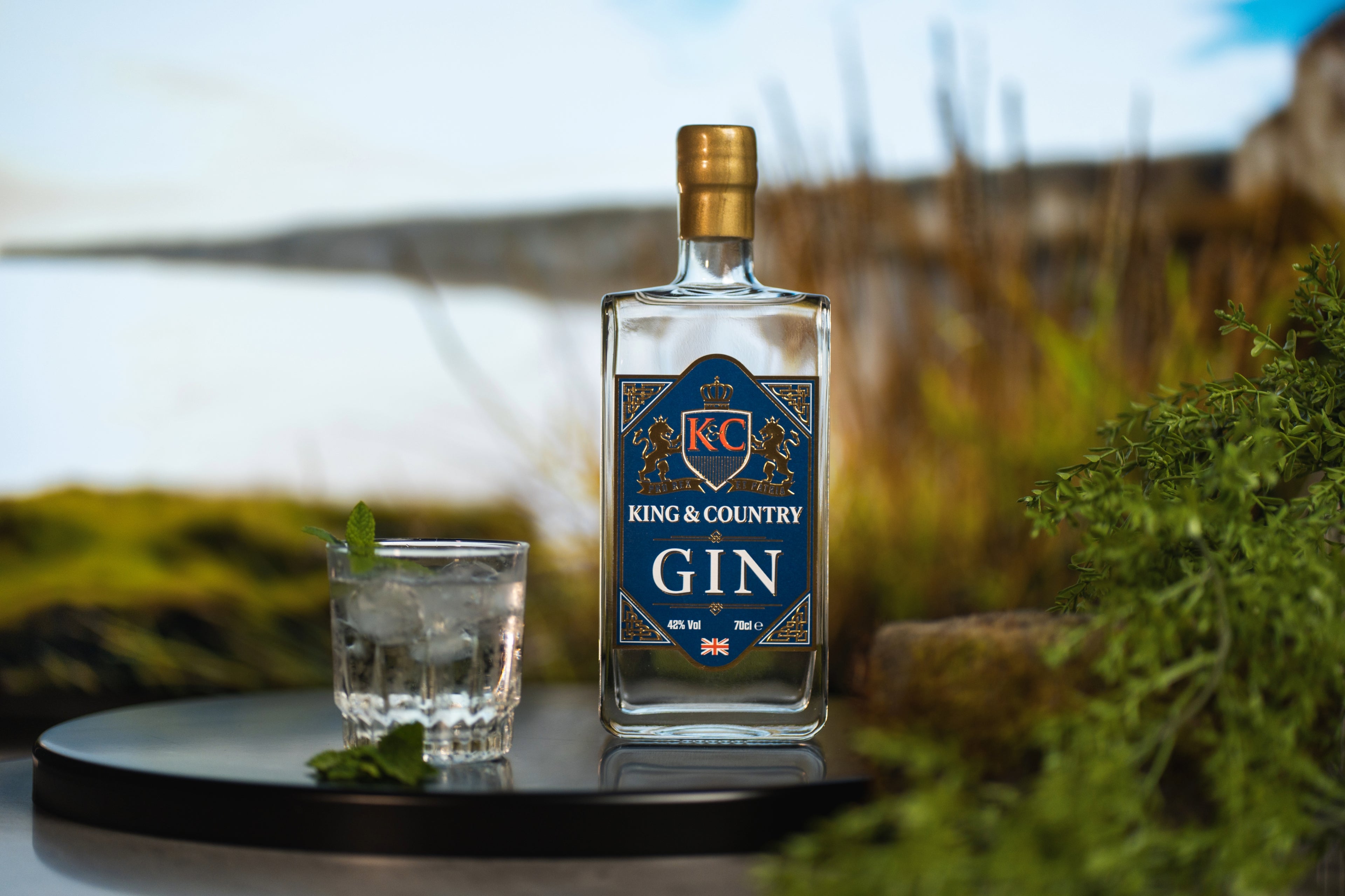 King & Country Gin bottle with a glass on a table outdoors